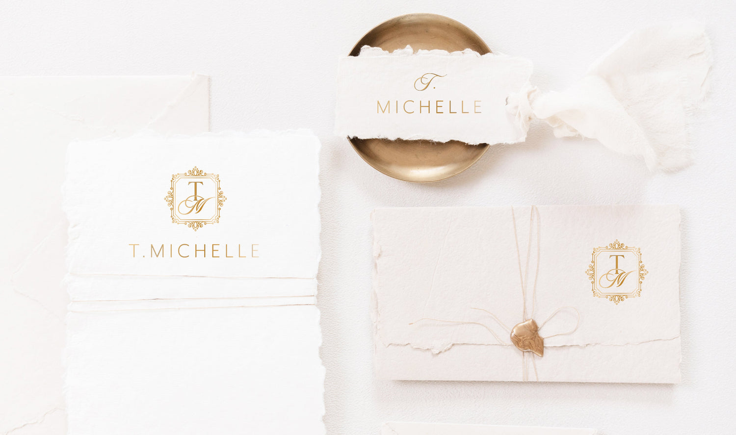 A styled flat-lay of a monogram logo suite featuring white and cream textured paper envelopes, a gold wax seal, and a gold monogrammed card on a white background with the text 'Full Logo Suite' at the bottom.