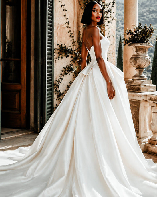 Woman in a white wedding dress standing in front of an elegant building with columns and decorative elements.